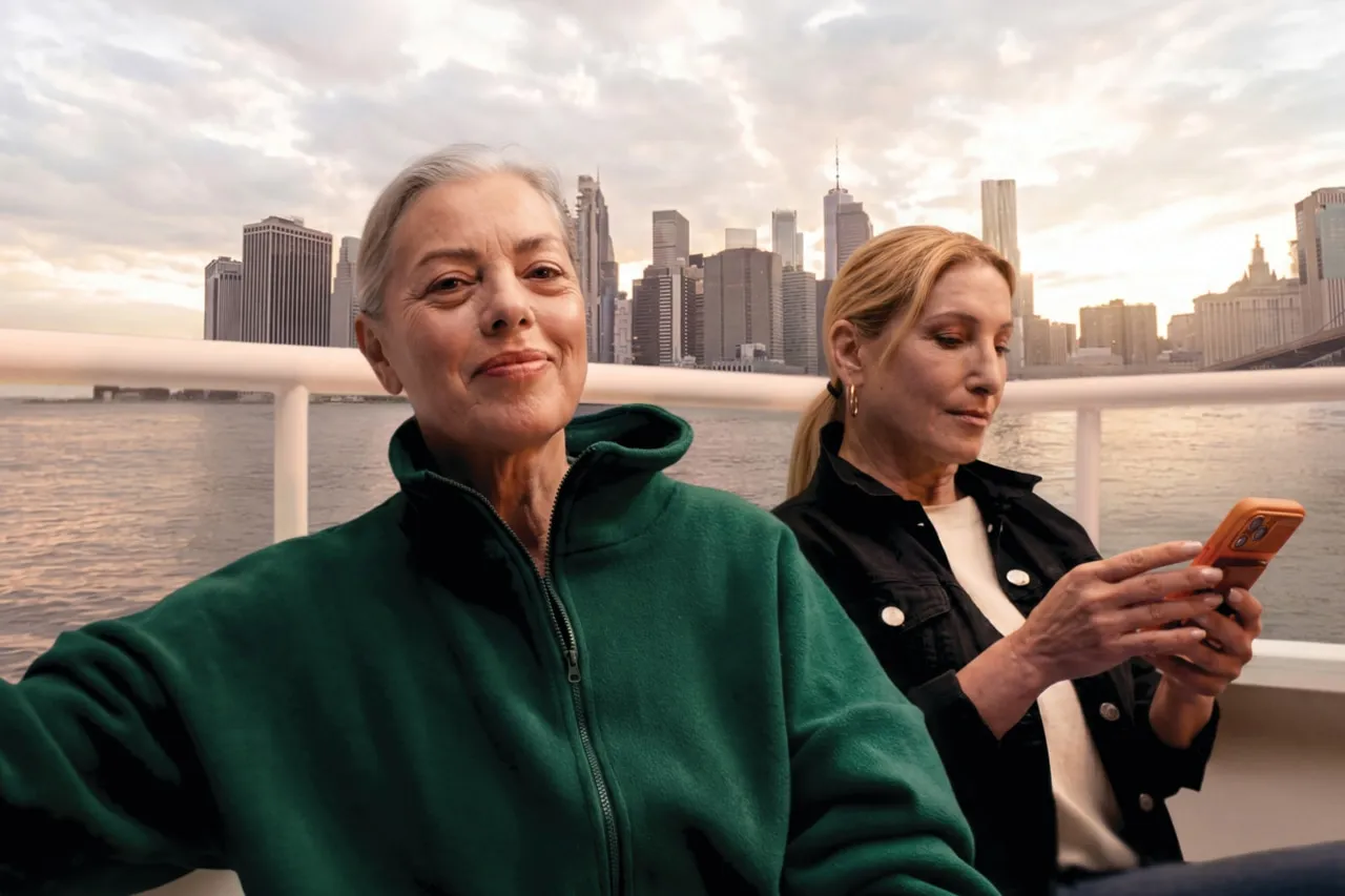 Two women talking on a boat at sunset with a city skyline behind them