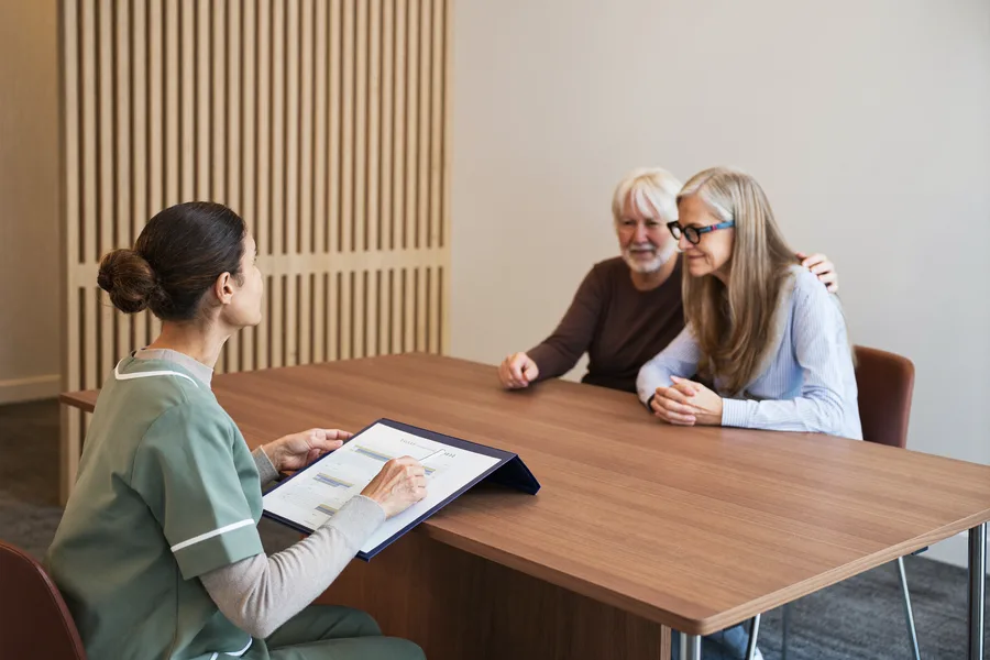 An audiologist pointing to a printed hearing chart while explaining the results to an older couple