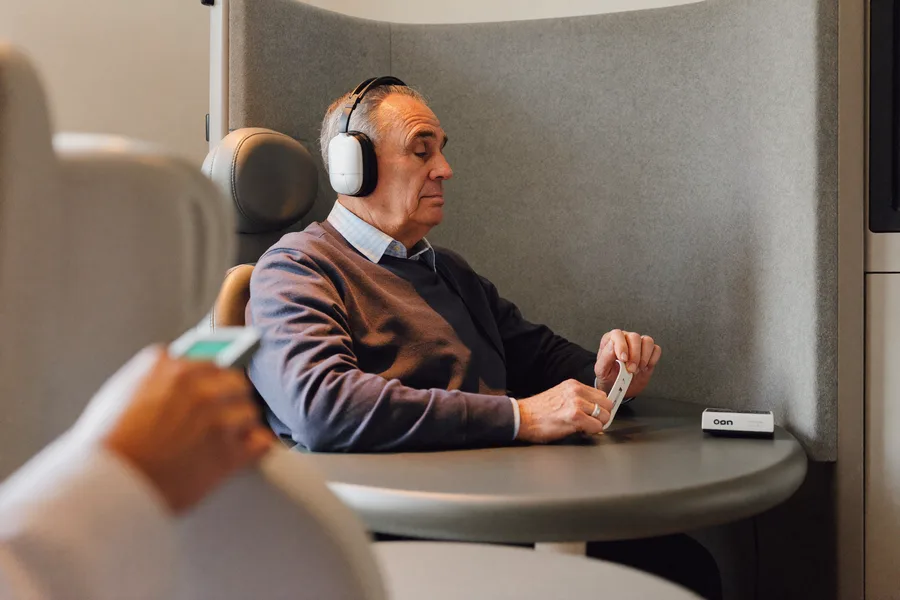 An older man wearing audiometry headphones inside a soundproof booth during a hearing test