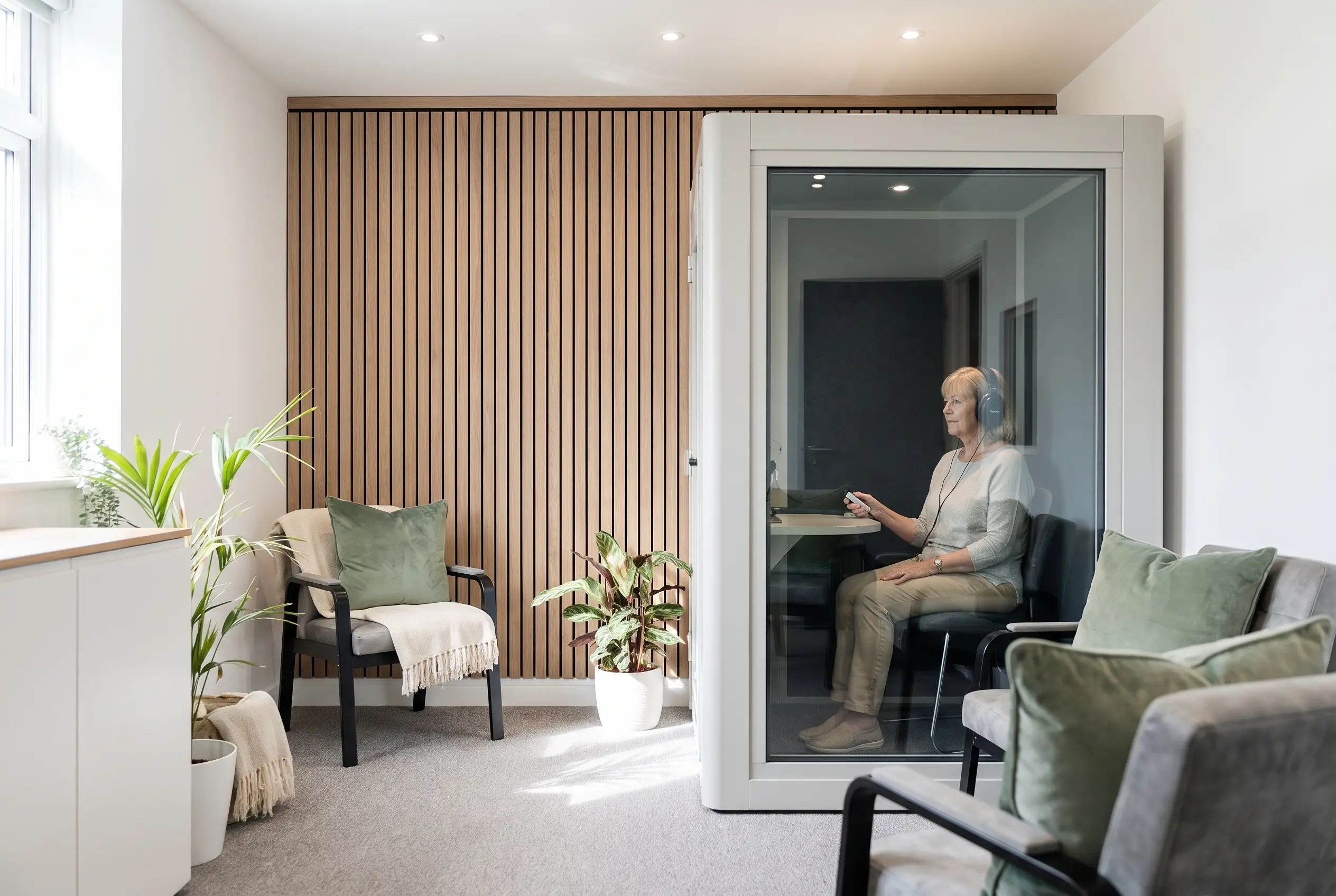 A patient seated in a glass soundproof booth during a hearing test at VIP Hearing Solutions