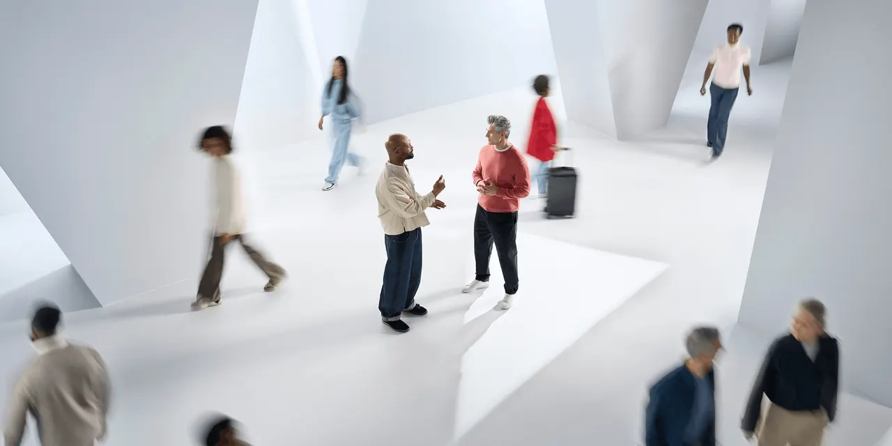 Two men talking in a shaft of light while a blurred crowd passes, from ReSound’s Sensia campaign