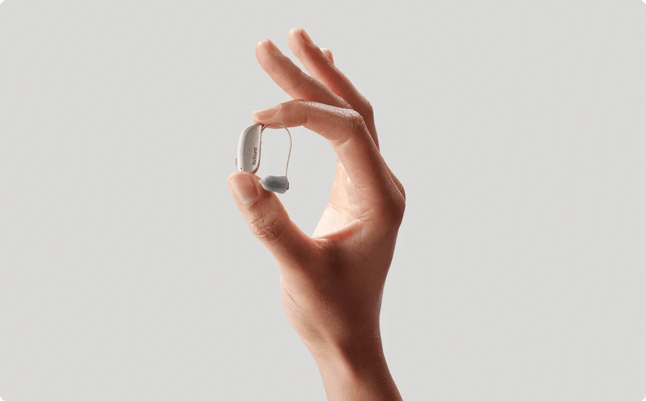 A ReSound Sensia microRIE hearing aid held in a hand