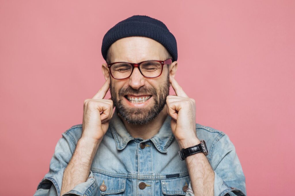 annoyed man covering both his ears with his fingers
