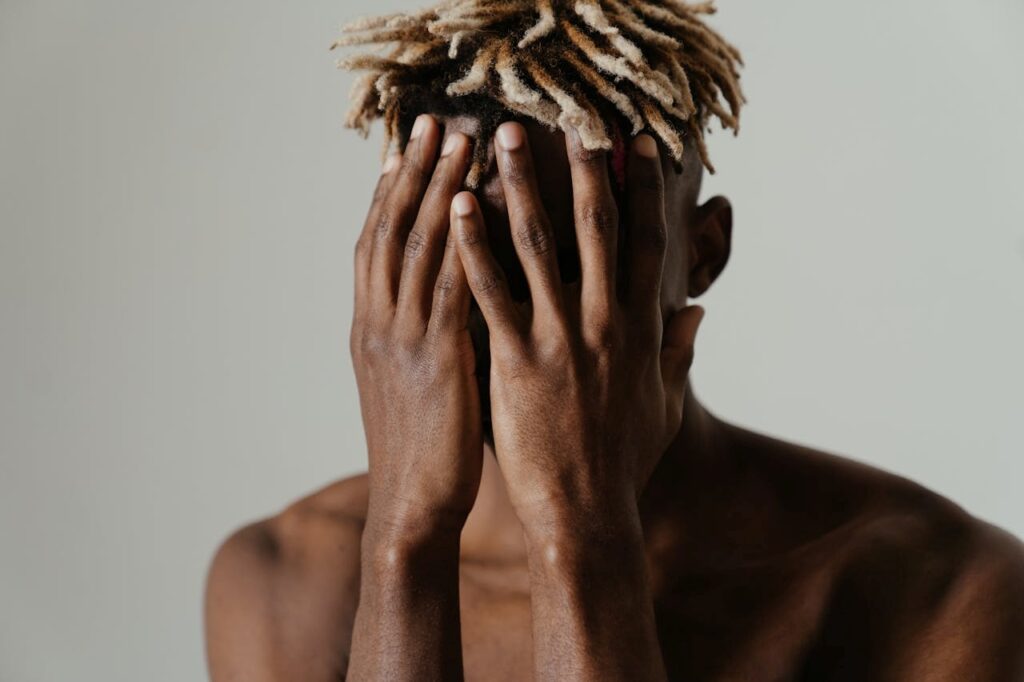man covering his face with both his hands