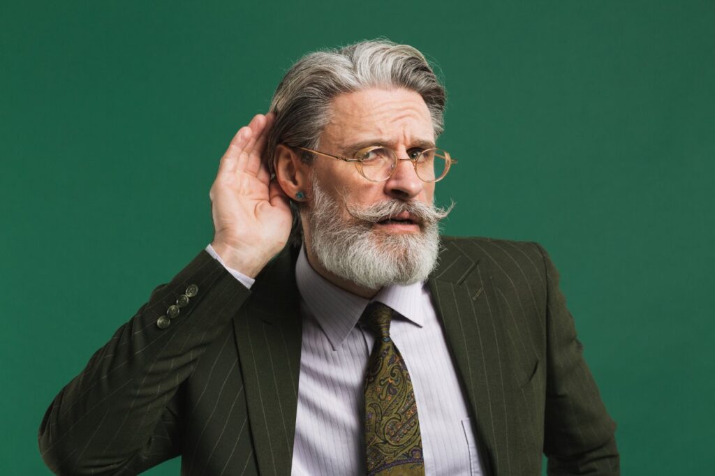 elderly man with beard having troubles with his hearing