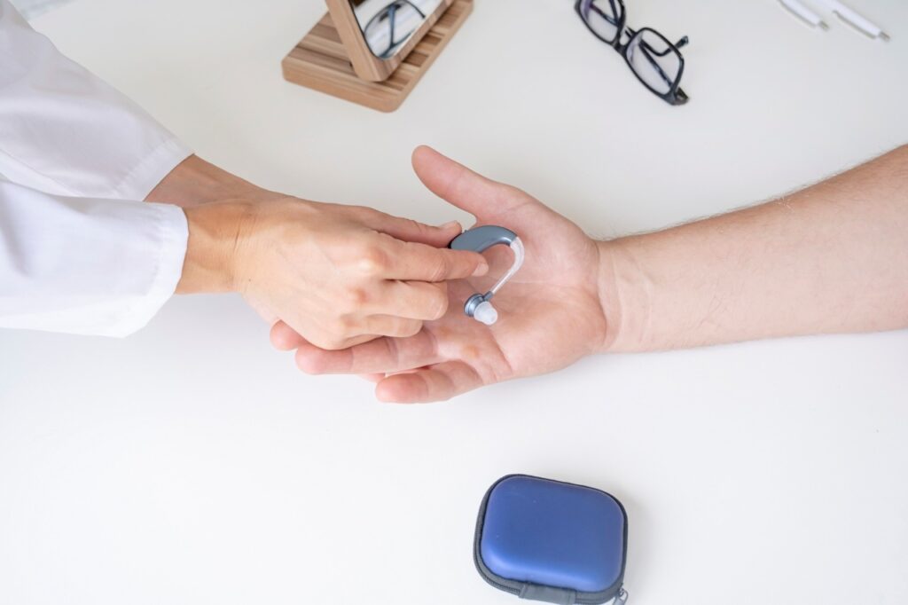 doctor handing over a hearing aid to a patient