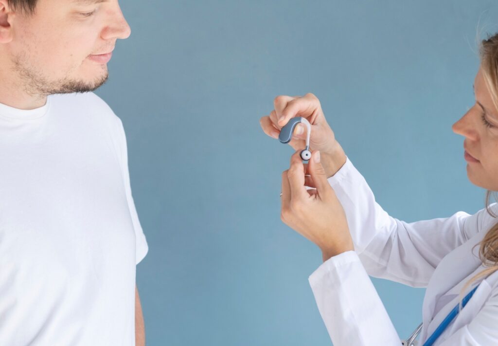 doctor showing hearing aid to a male patient