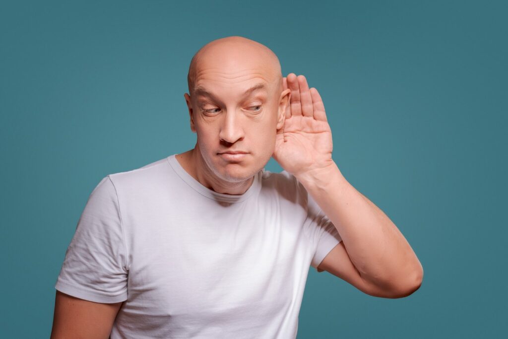 a man with no hair having trouble with hearing