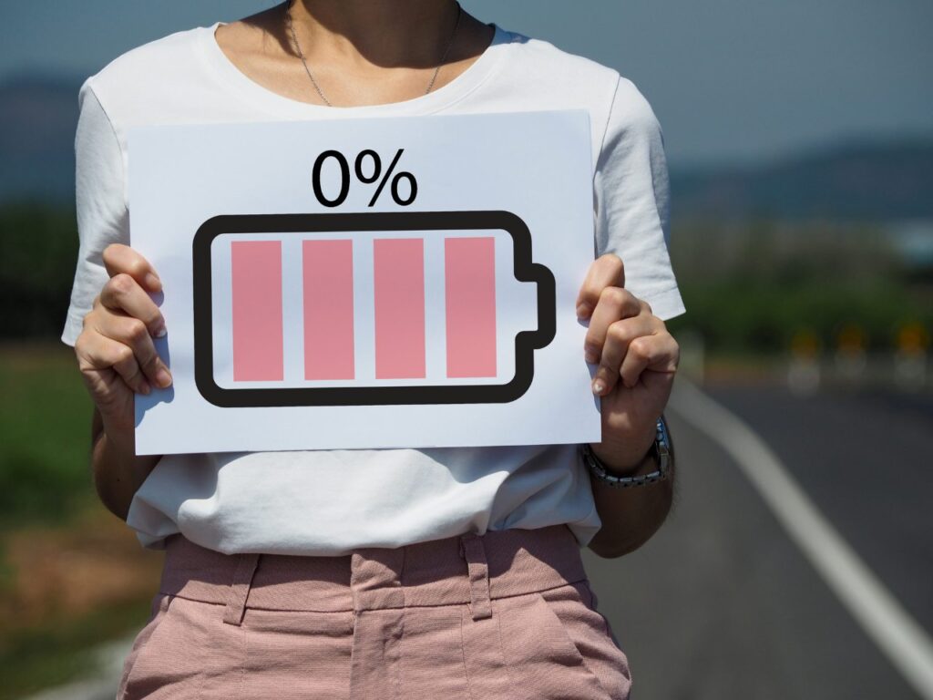 girl standing on side of the road holding a paper with a print of battery icon