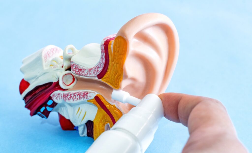 Using a spray to clean the ears, clogged by the secretion of the ear