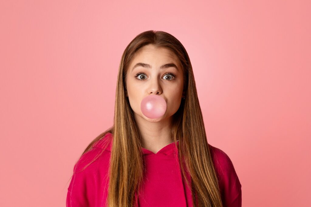young woman blowing a bubble with chewing gum
