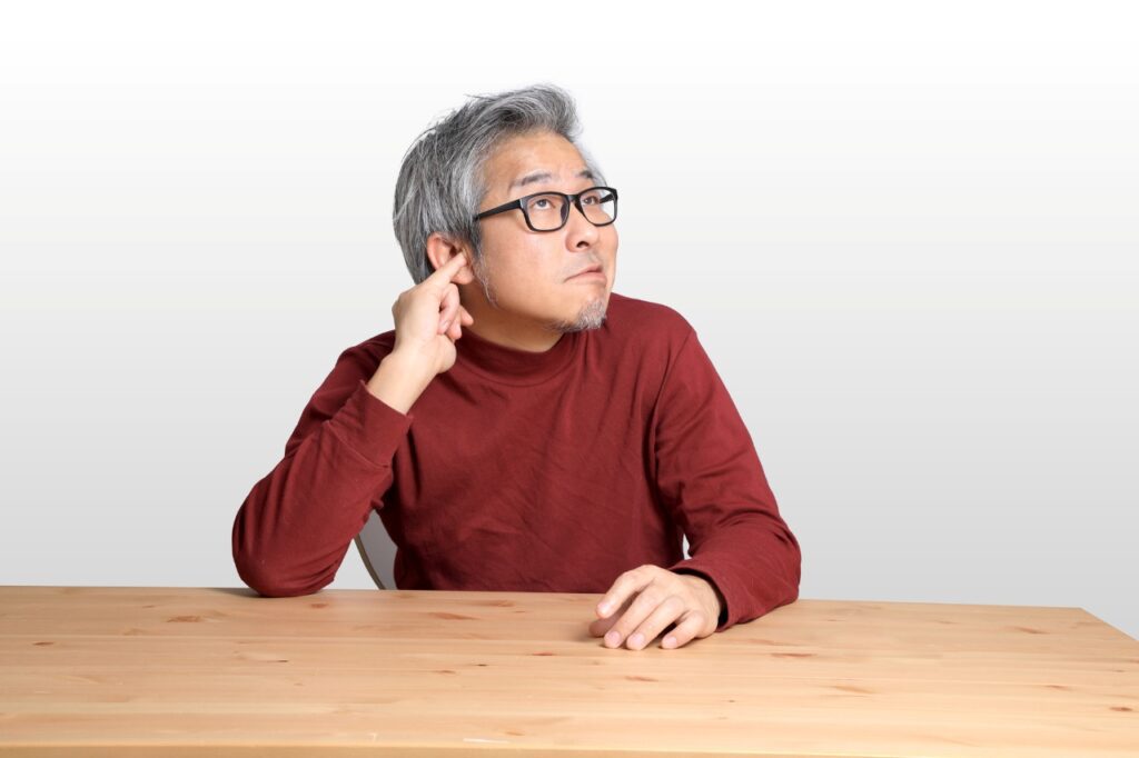 senior asian man with his pinky in his ear