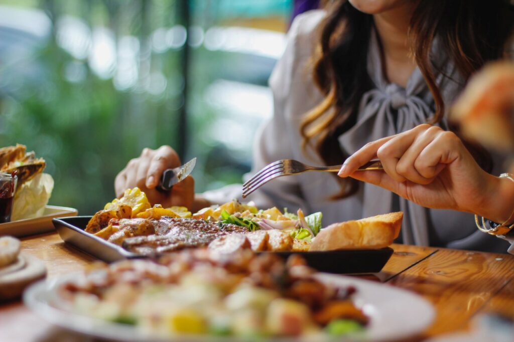 close up shot of food on table with woman eating