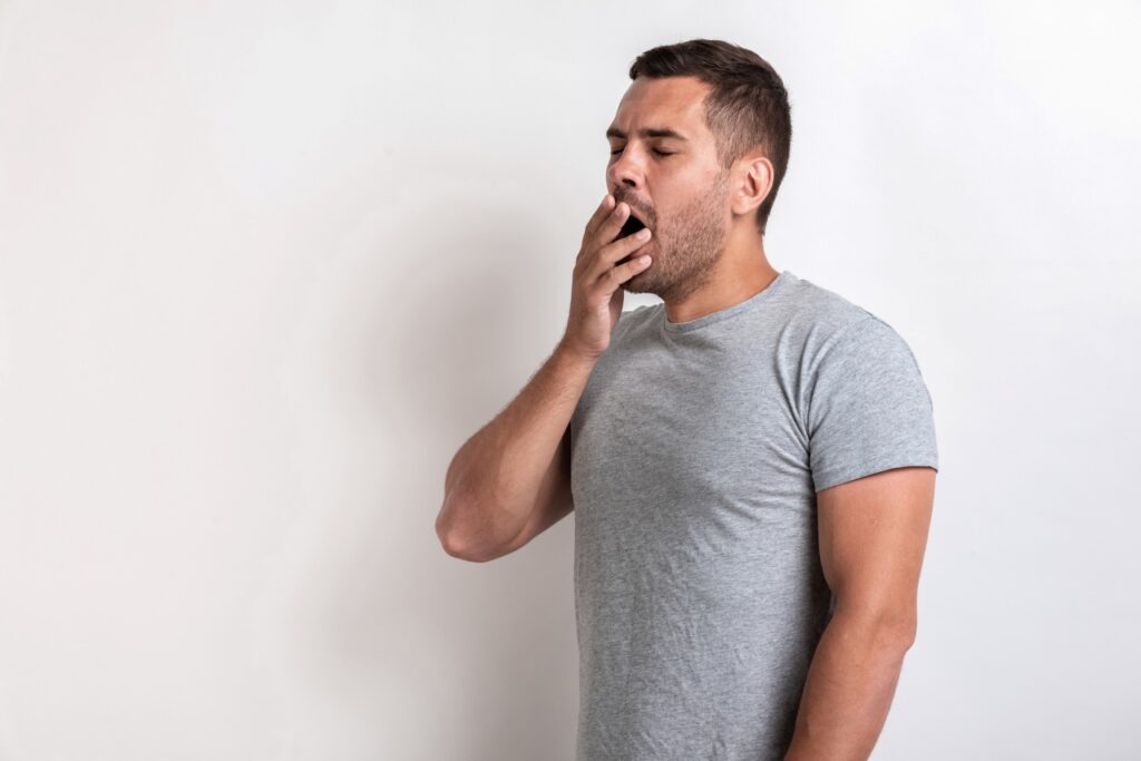 man wearing a grey shirt yawning