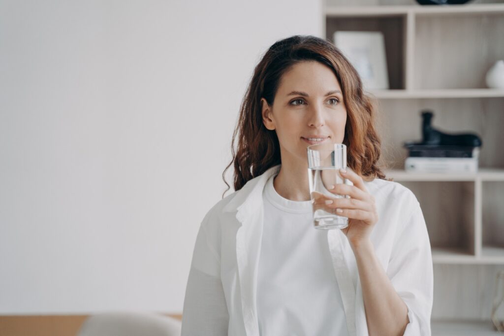 Happy girl is holding glass of water and smiling