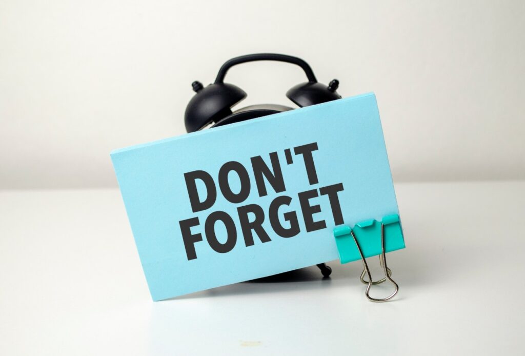 words don't forget on a blue sticky note stuck to an alarm clock