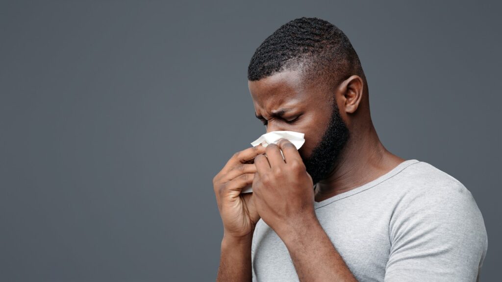 man blowing his nose on a tissue paper