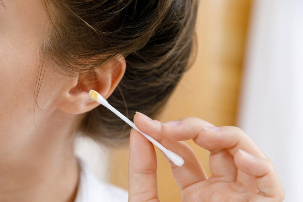 woman trying to clean her ears using q tip