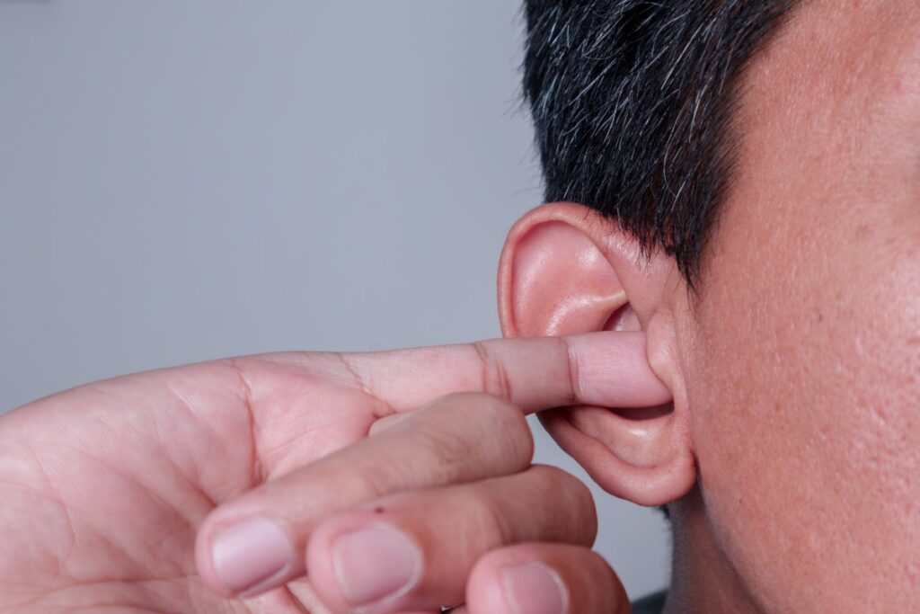 man sticking his pinky finger in his ear