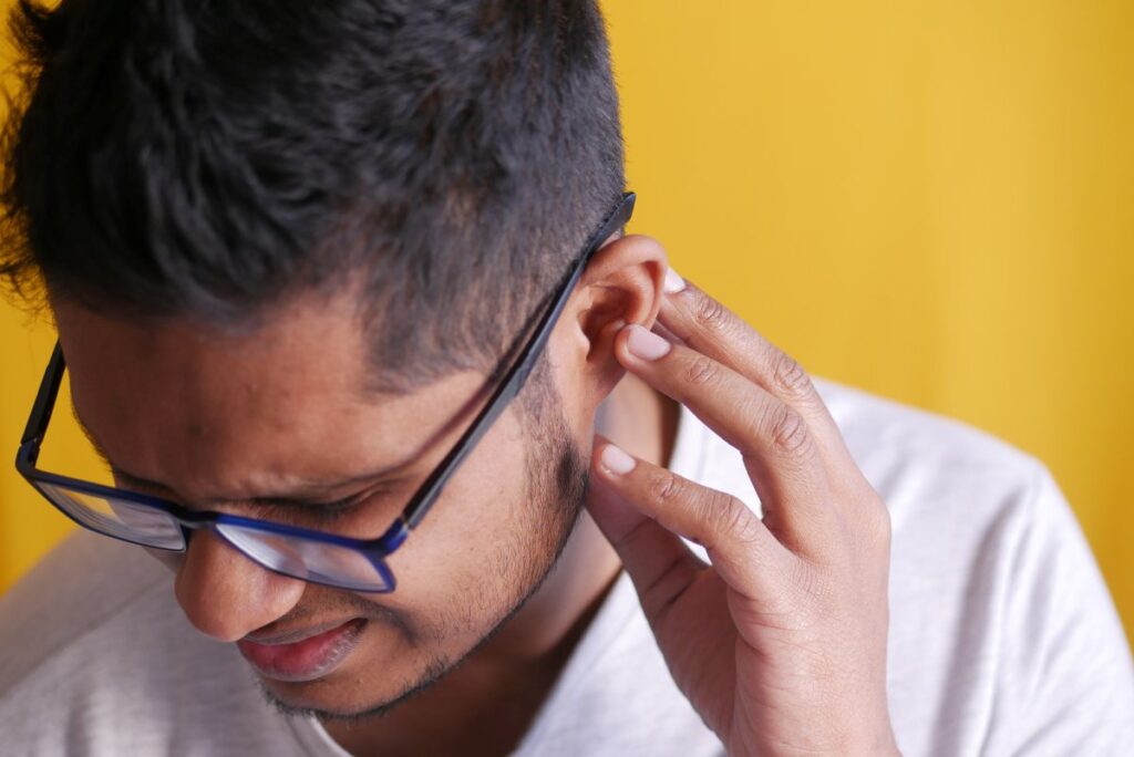 young man having ear pain touching his painful ear