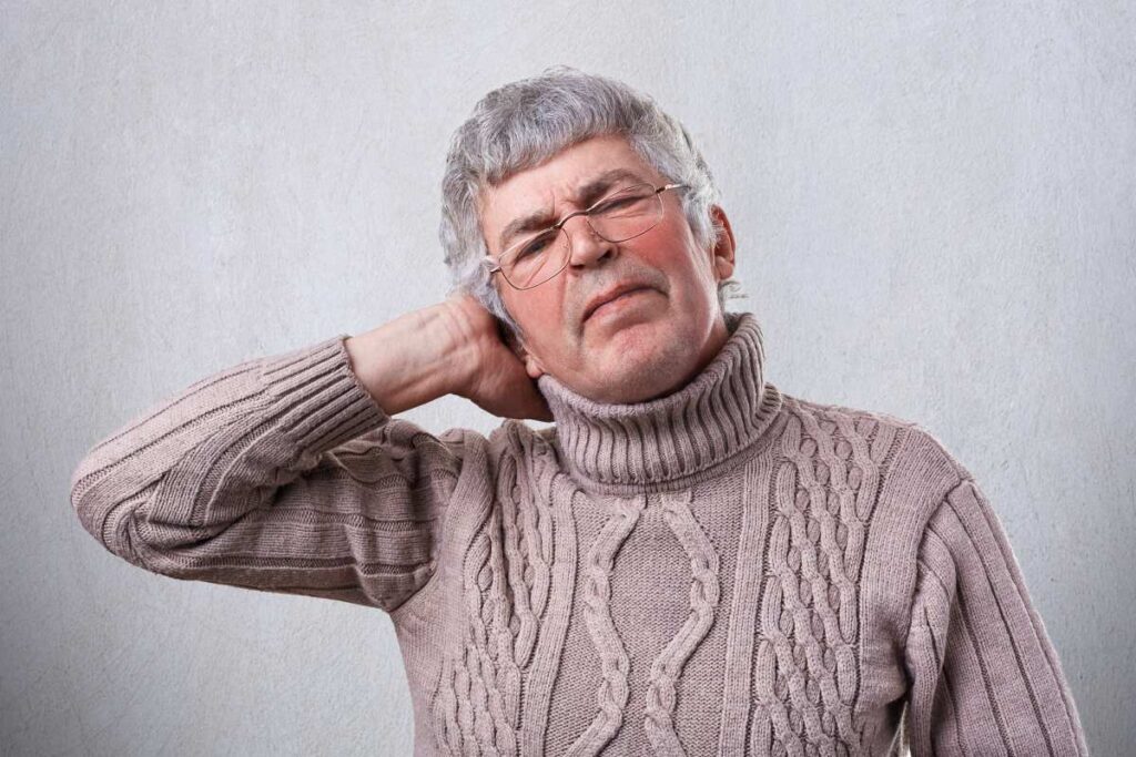 senior man wearing glasses with his hand on his ear