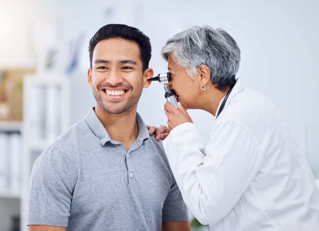 smiling man getting his ear checked by a doctor