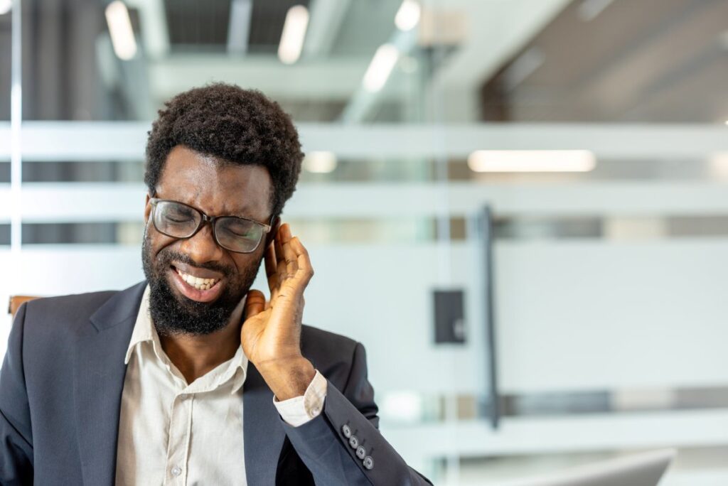 Adult person experiencing discomfort and holding his ear