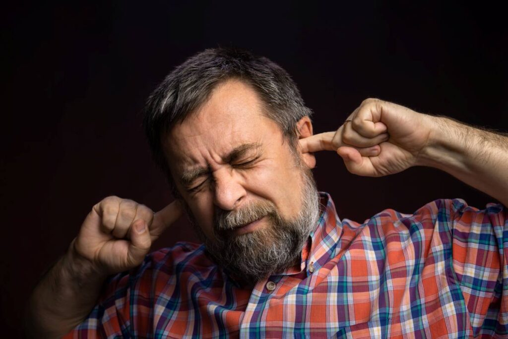 young man having ear pain touching his painful ear