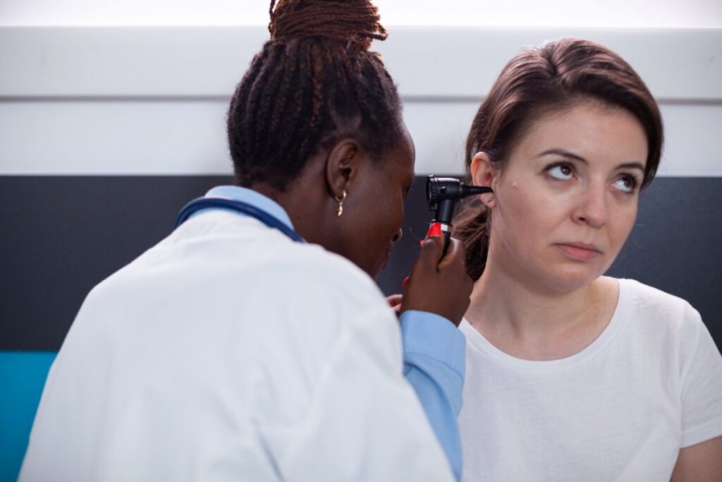 Otology specialist doctor checking for patient earache, ruptured eardrum, tinnitus and deafness ear symptoms
