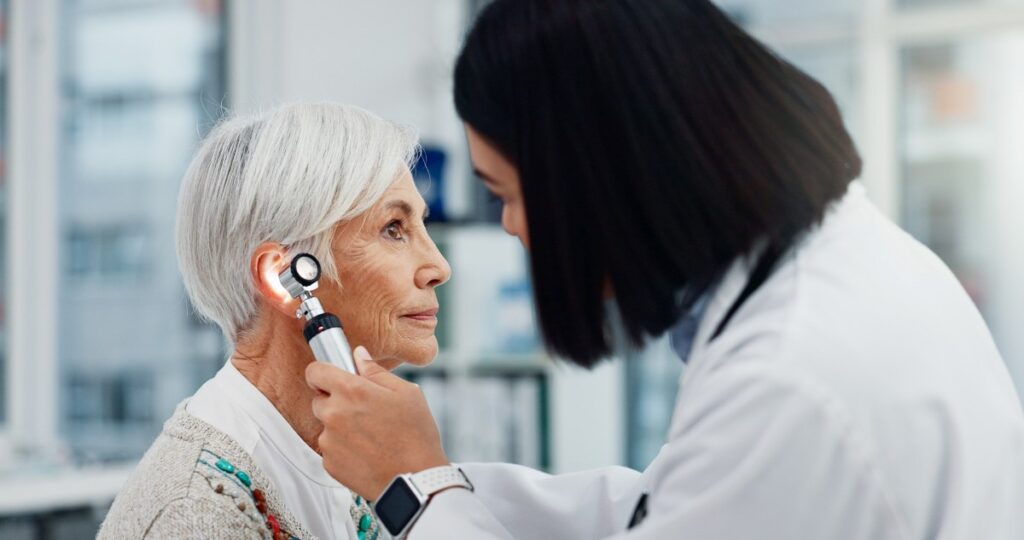 Otoscope, otolaryngology or medical professional with elderly person for wellness or help in hospital