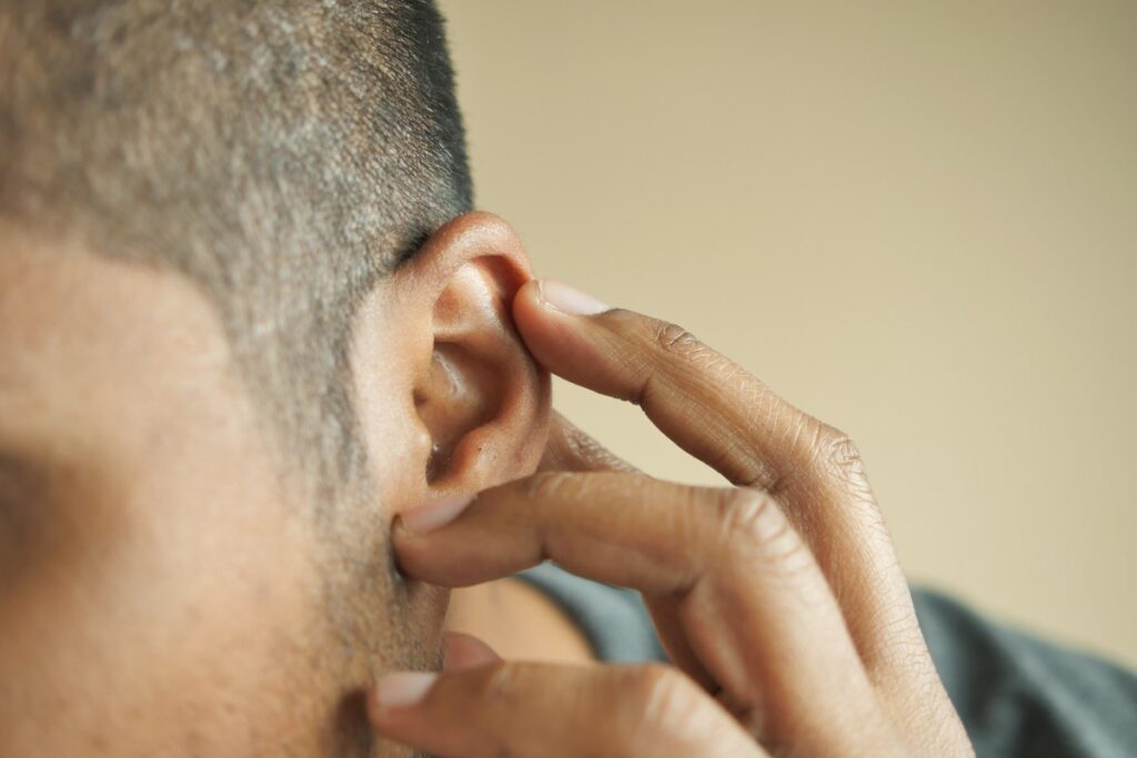young man having ear pain touching his painful ear